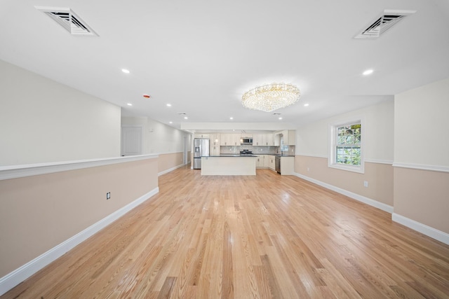 unfurnished living room with baseboards, visible vents, and light wood-style flooring