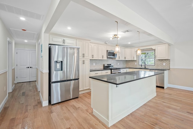kitchen with backsplash, visible vents, dark countertops, light wood-type flooring, and stainless steel appliances