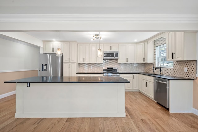 kitchen with dark countertops, appliances with stainless steel finishes, a sink, and a center island