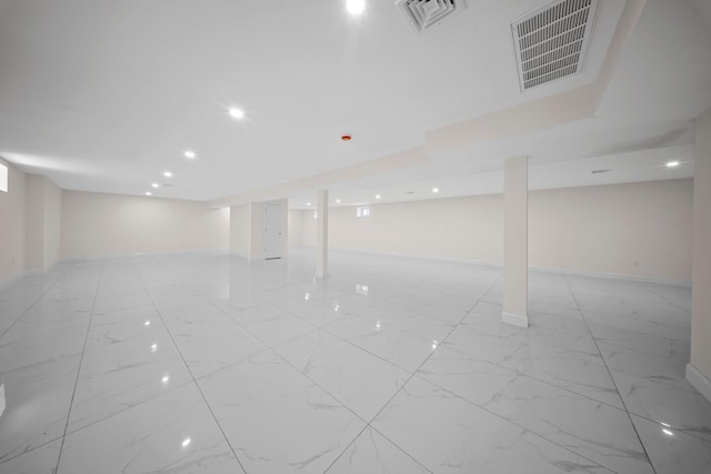 finished basement featuring baseboards, marble finish floor, and visible vents