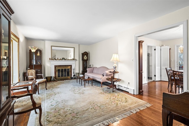 living room with a fireplace with flush hearth, wood finished floors, and a baseboard radiator