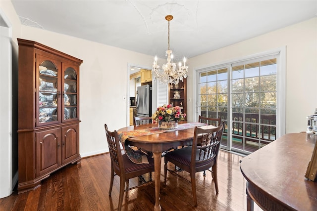 dining area with dark wood finished floors, an inviting chandelier, and baseboards
