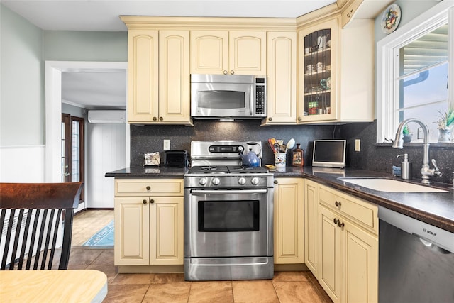 kitchen featuring stainless steel appliances, a sink, dark countertops, and cream cabinets