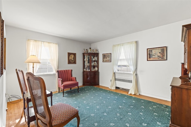 sitting room with radiator heating unit, baseboards, and wood finished floors