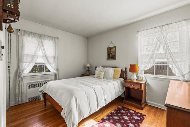 bedroom with wood-type flooring, baseboards, and radiator