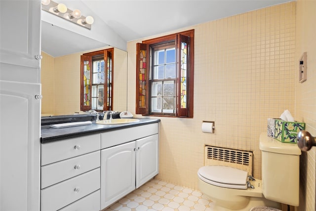 bathroom with radiator, tile walls, toilet, and vanity