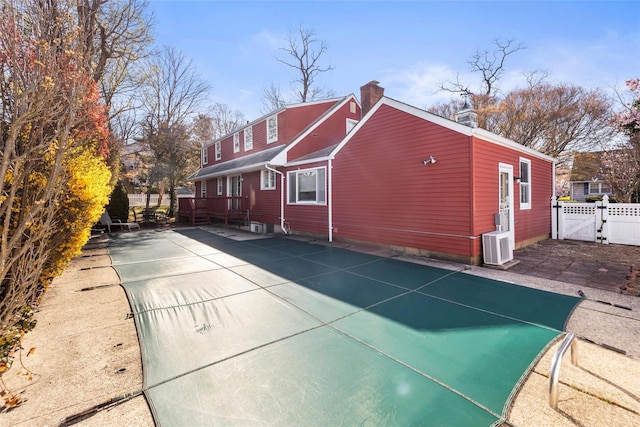 exterior space with a gate, a chimney, fence, a patio, and a wooden deck