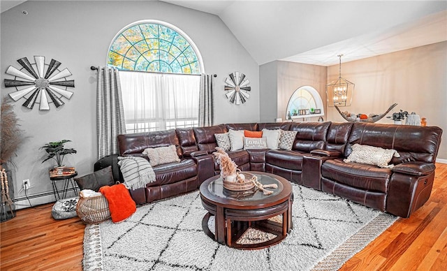 living area featuring baseboard heating, vaulted ceiling, a notable chandelier, and wood finished floors