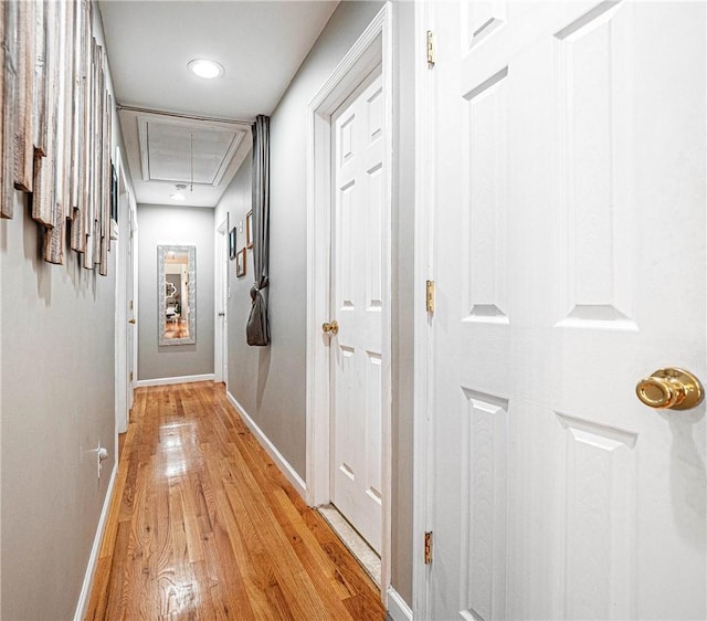 hallway featuring attic access, light wood-style floors, baseboards, and recessed lighting