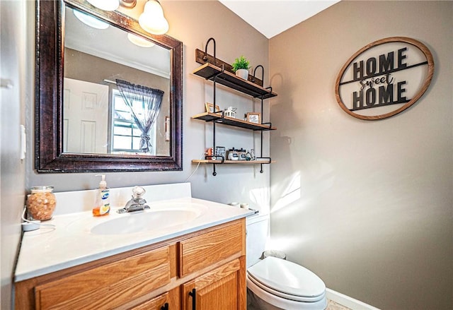 bathroom with toilet, vanity, and baseboards