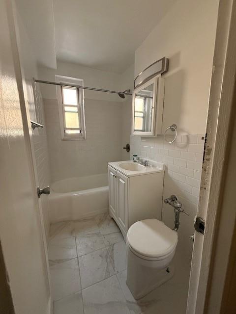 34-15 74th St Unit 4H, Jackson Heights, NY 11372 - bathroom featuring vanity, toilet, shower / washtub combination, marble look tiles, and tile walls
