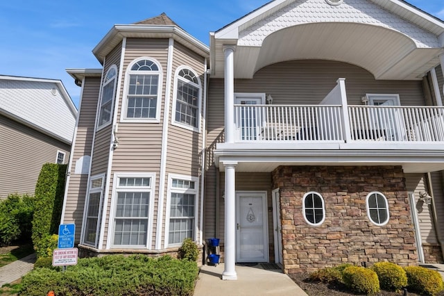 view of front facade with stone siding and a balcony