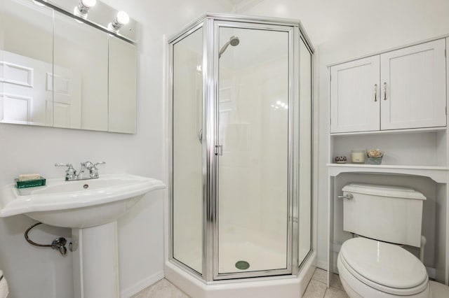 full bath with toilet, a sink, a stall shower, baseboards, and tile patterned flooring