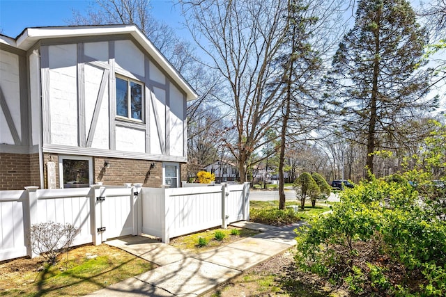 view of home's exterior with a gate, brick siding, and fence private yard
