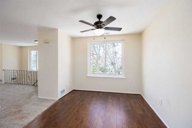 unfurnished room with wood finished floors, visible vents, baseboards, and ceiling fan