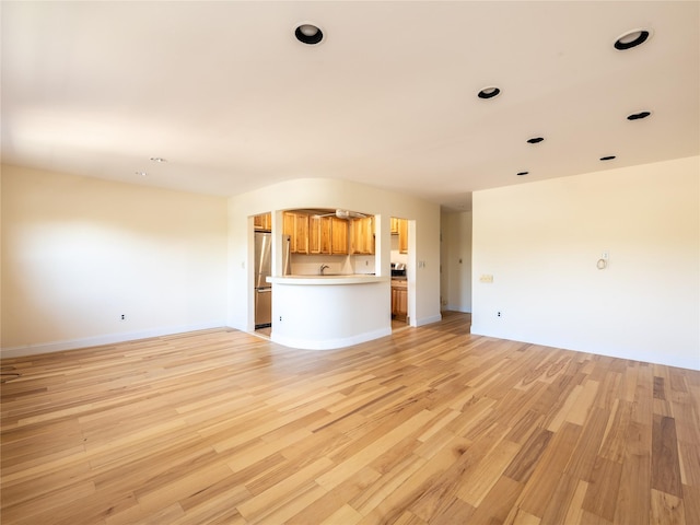 unfurnished living room with recessed lighting, baseboards, and light wood-type flooring