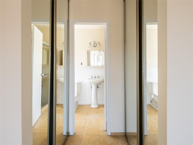 corridor featuring a sink and light tile patterned floors