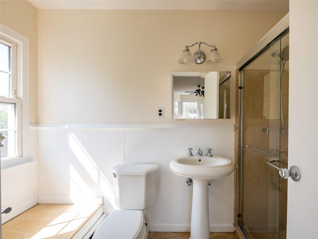 full bath featuring wainscoting, toilet, and a shower stall