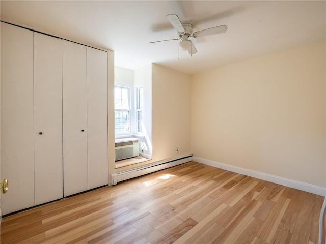 unfurnished bedroom with ceiling fan, baseboard heating, light wood-type flooring, baseboards, and a closet