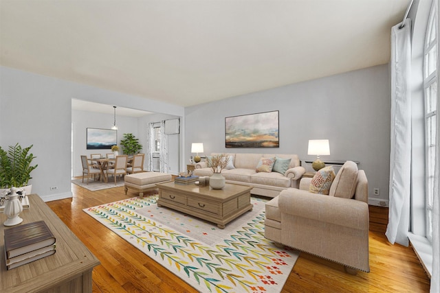 living room featuring light wood-style flooring, baseboards, and plenty of natural light