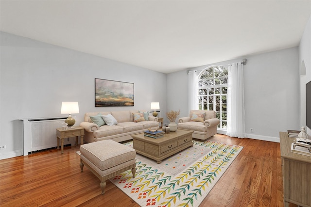 living area featuring light wood-style flooring, radiator heating unit, and baseboards