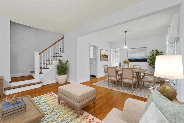 living room featuring baseboards, stairway, and wood finished floors