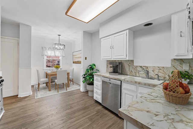 kitchen with stainless steel dishwasher, white cabinets, a sink, wainscoting, and light wood finished floors