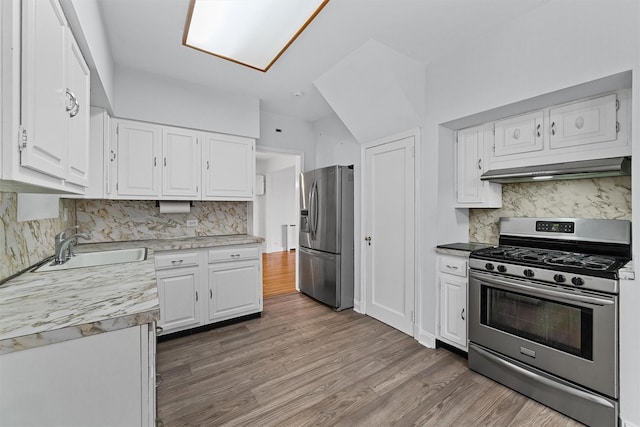 kitchen with under cabinet range hood, white cabinetry, backsplash, and appliances with stainless steel finishes
