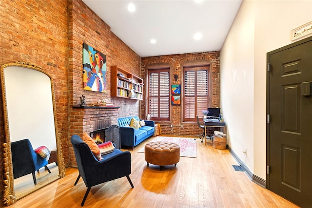 living area featuring a brick fireplace, recessed lighting, hardwood / wood-style floors, and brick wall