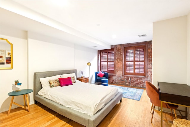 bedroom featuring brick wall, visible vents, hardwood / wood-style flooring, and baseboards