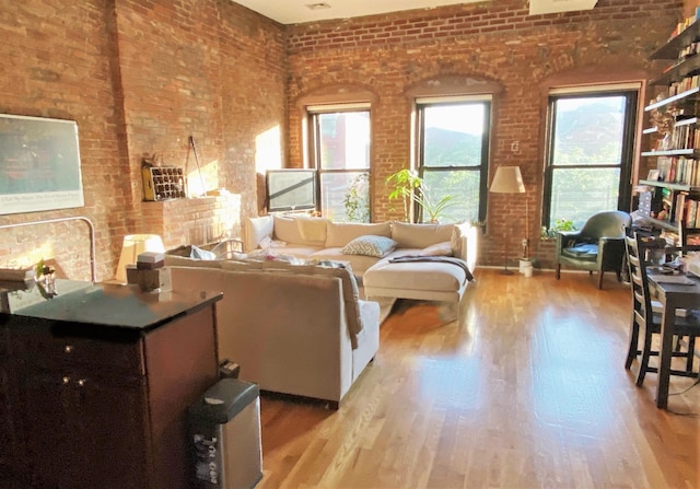 living area with light wood-style floors and brick wall