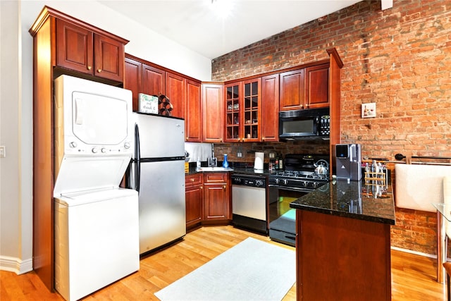 kitchen with stacked washer and dryer, glass insert cabinets, black appliances, and light wood finished floors