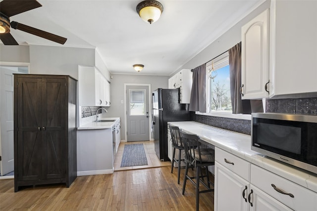24 Southwood Ln, North Babylon, NY 11703 - kitchen featuring freestanding refrigerator, a sink, stainless steel microwave, and a healthy amount of sunlight