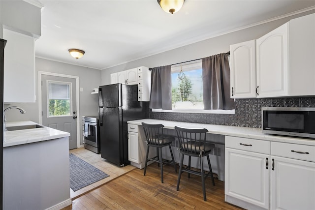 24 Southwood Ln, North Babylon, NY 11703 - kitchen featuring crown molding, tasteful backsplash, a sink, white cabinets, and appliances with stainless steel finishes