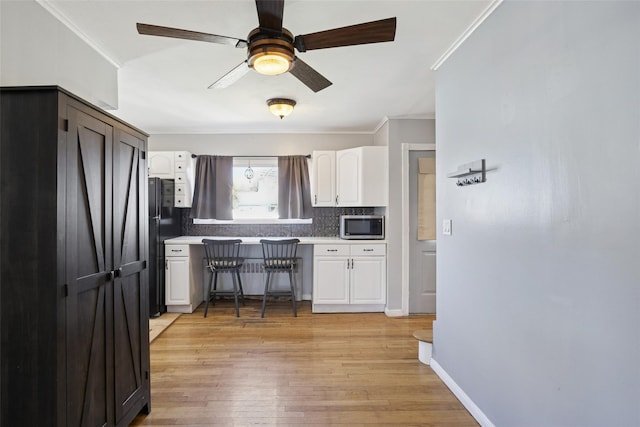 24 Southwood Ln, North Babylon, NY 11703 - kitchen featuring white cabinets, ceiling fan, stainless steel microwave, and ornamental molding