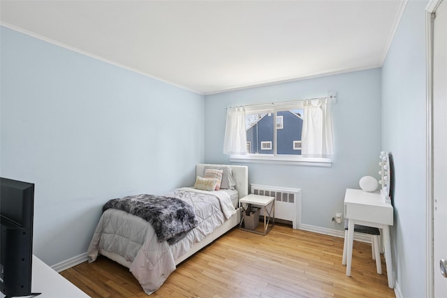 24 Southwood Ln, North Babylon, NY 11703 - bedroom with radiator heating unit, light wood-style flooring, baseboards, and crown molding