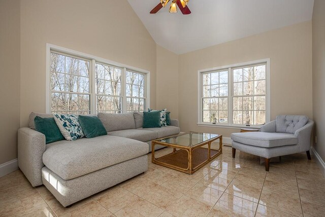 living room with ceiling fan, high vaulted ceiling, light tile patterned flooring, and baseboards