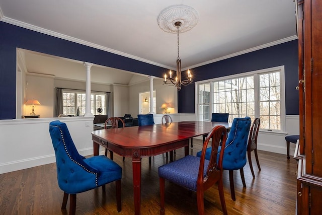 dining area with a notable chandelier, baseboards, crown molding, ornate columns, and wood finished floors