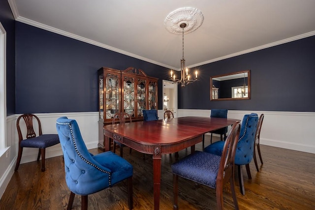 dining area featuring wood finished floors, an inviting chandelier, ornamental molding, and a wainscoted wall