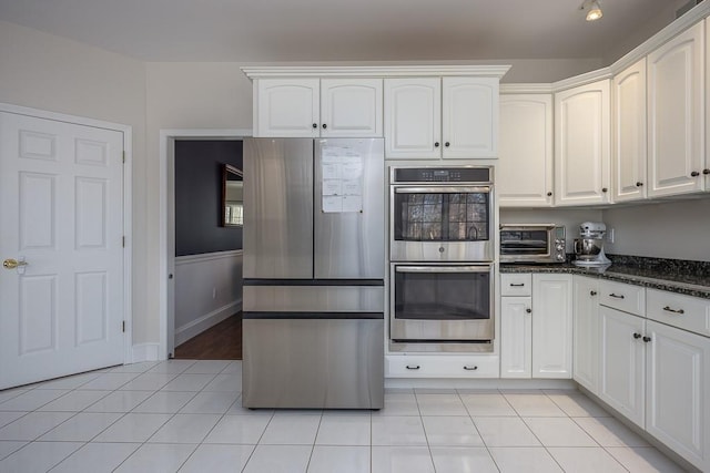 kitchen with light tile patterned floors, white cabinets, appliances with stainless steel finishes, and a toaster