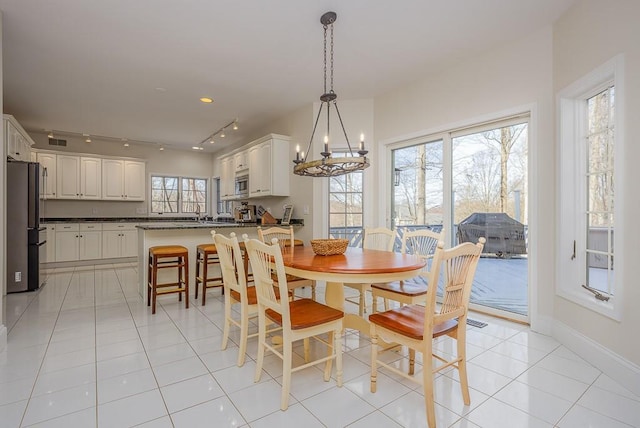 dining space featuring track lighting, visible vents, a chandelier, light tile patterned flooring, and baseboards