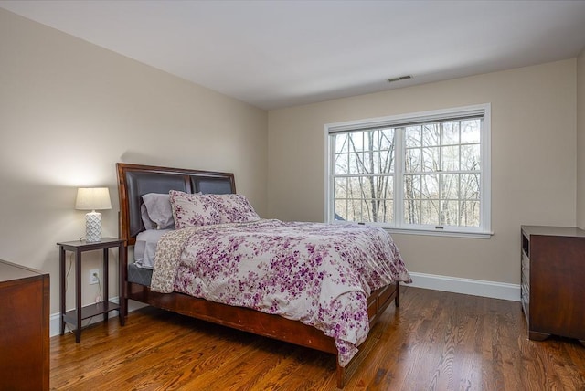 bedroom with visible vents, baseboards, and wood finished floors
