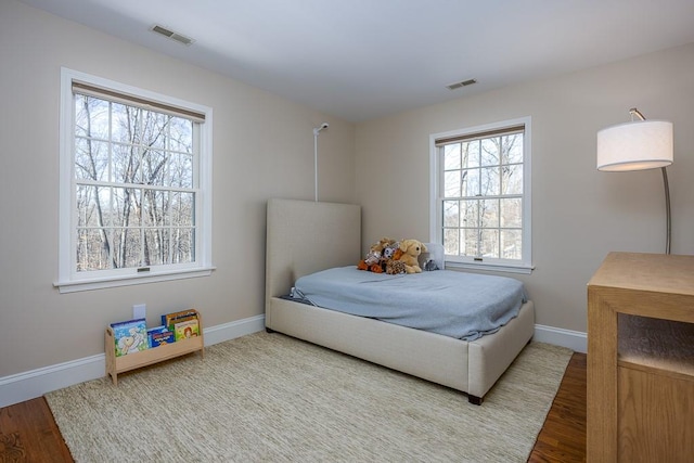 bedroom with visible vents, baseboards, and wood finished floors