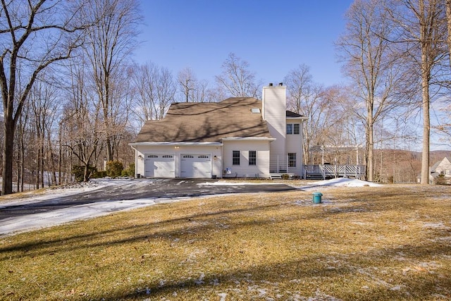 view of home's exterior with an attached garage, driveway, and a chimney