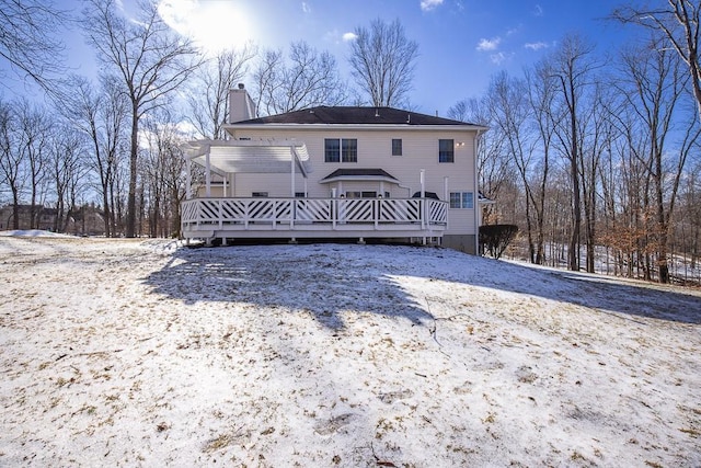 snow covered property with a pergola, a wooden deck, and a chimney