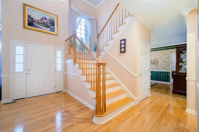 entrance foyer with wallpapered walls, hardwood / wood-style floors, and stairway