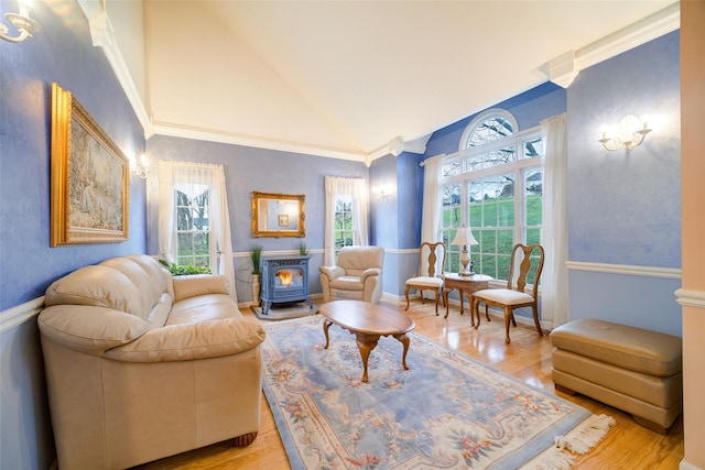 living area featuring light wood-type flooring, vaulted ceiling, a wood stove, and a healthy amount of sunlight