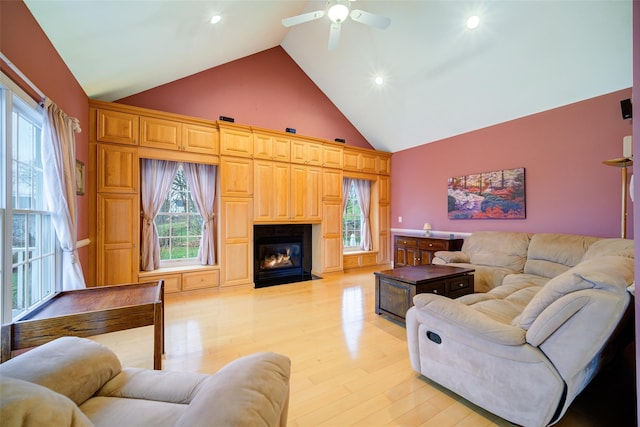 living room featuring high vaulted ceiling, a ceiling fan, a fireplace with flush hearth, light wood finished floors, and recessed lighting