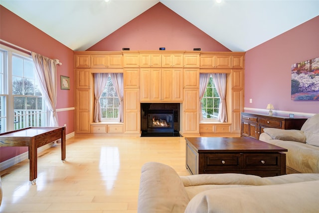 living area with a fireplace with flush hearth, light wood-style flooring, a wealth of natural light, and baseboards