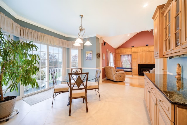 dining room with a chandelier, lofted ceiling, a fireplace, and ornamental molding